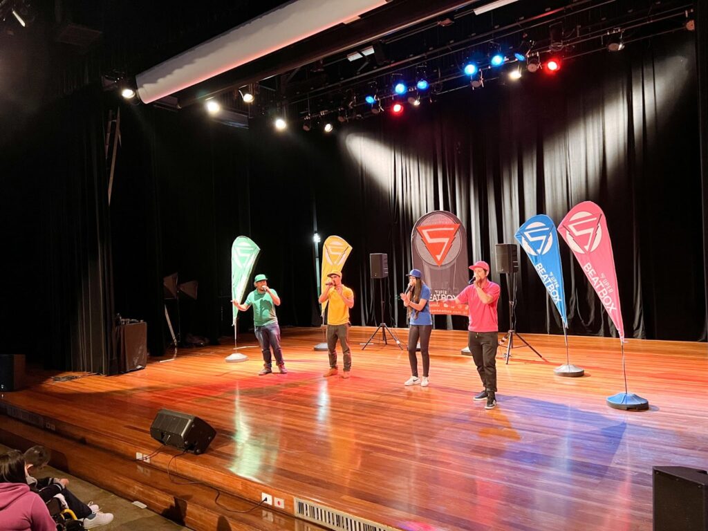Músicos no palco de um teatro ministrando curso de beatbox.