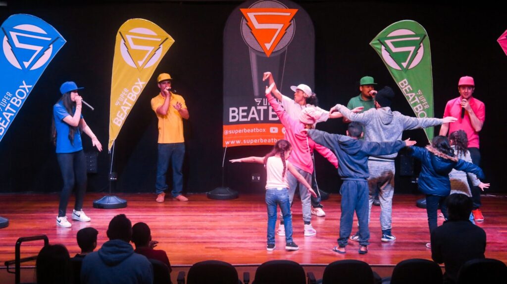 Dinâmica de hiphop durante curso de beatbox no palco de um teatro.