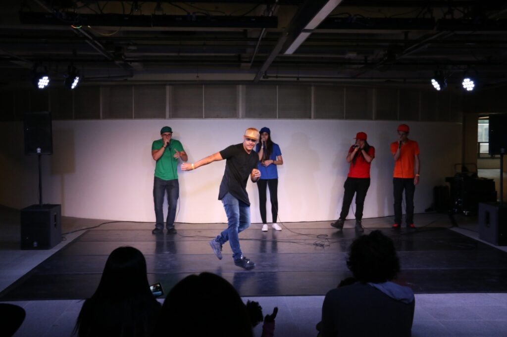 Apresentação em palco de eventos com homem dançando música de funk enquanto músicos fazem o beatbox